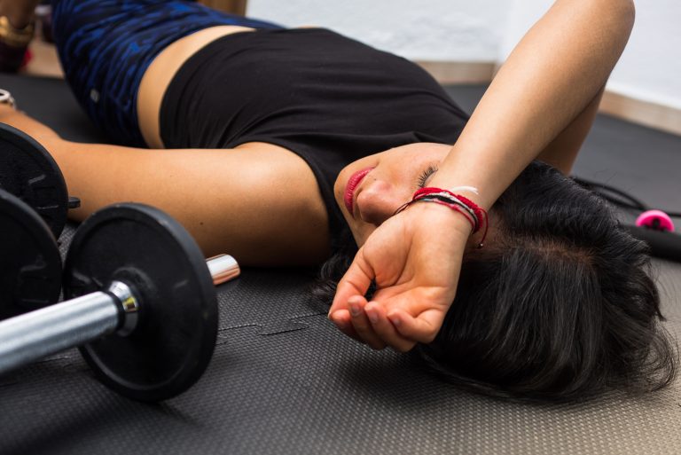 Closeup shot of an exhausted woman lying on the floor after exercise and workout